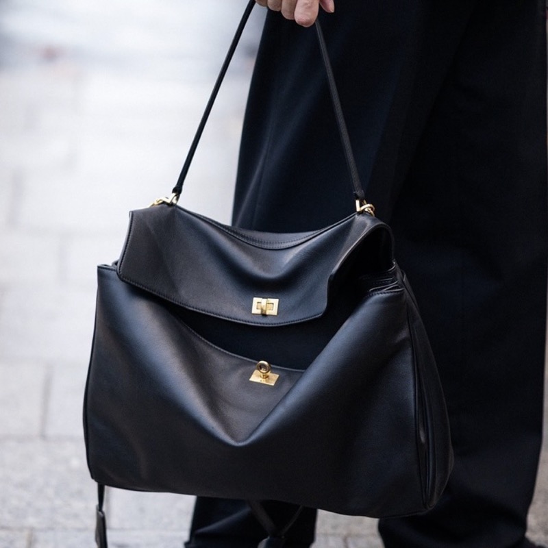 A slouchy black leather top-handle bag with two gold turn-locks